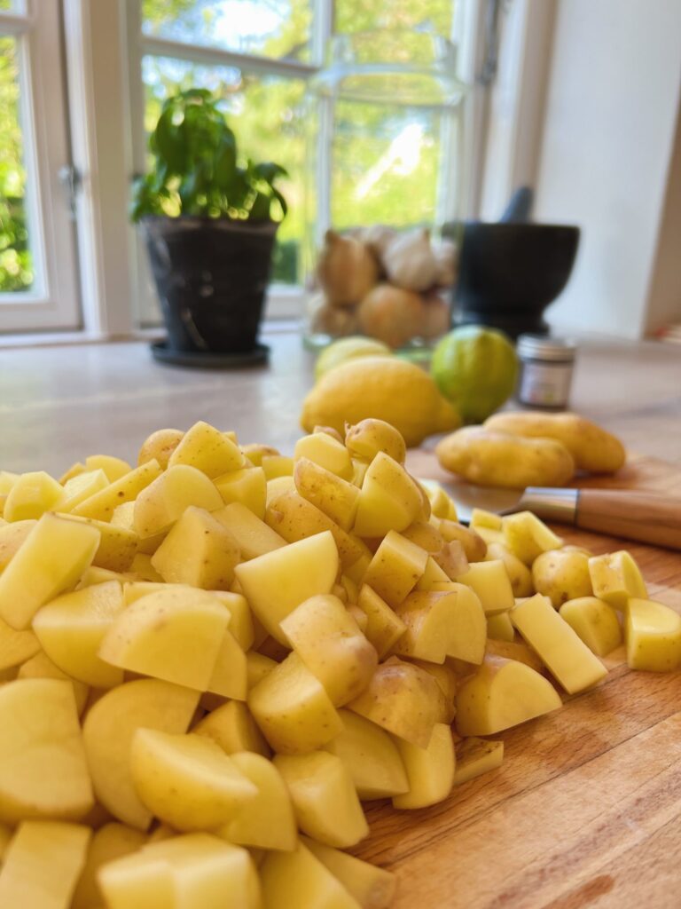 kartofler der er skåret i små tern og ligger på et skærebræt klar til at lave brasede kartofler