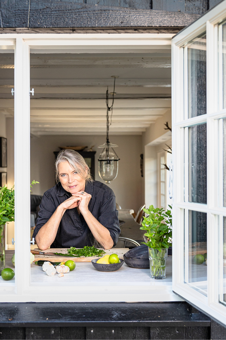 Dominique står i køkkenvindue og laver salat.