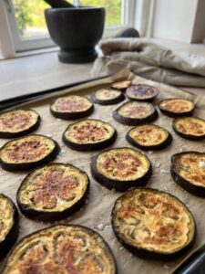 Bagte aubergineskiver på bageplade til lun tomat- og auberginesalat