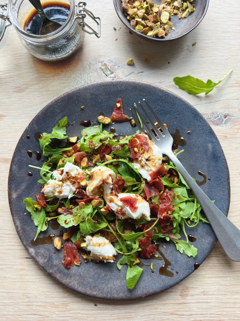 Portionsanrettet figencarpaccio med burrata, rucola, sprød parmaskinke og pistacienødder